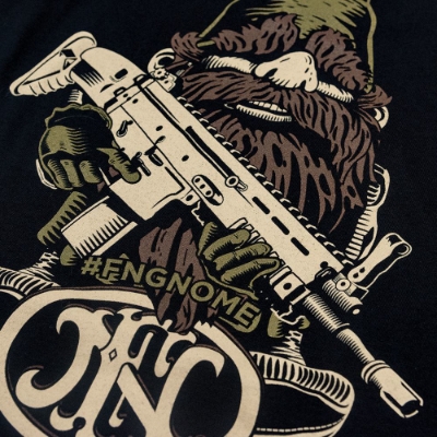 Black t-shirt with an illustration of the classic FN America Gnome in the front center.  He is holding a golden machine gun, and wearing a green hat. It is written "#FNGNOME" under him, with a dark version of the FN America logo under that.