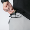 A man wearing light gray FN-branded drawstring shorts demonstrates concealed carry by revealing a  magazine secured in a back pocket