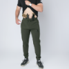 Man wearing dark green drawstring pants branded with FN Firearms, showing a pistol and spare magazine holstered inside the waistband with a tactical belt system